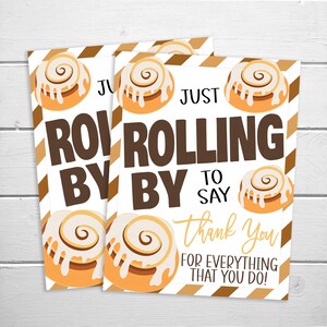 May include: A white card with brown stripes and a cinnamon roll design. The card says "Just rolling by to say thank you for everything that you do!"
