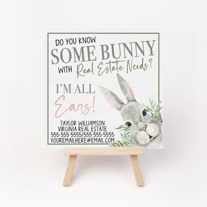 May include: A white card with a cartoon bunny peeking out from behind green leaves. The text on the card reads "Do you know some bunny with real estate needs? I'm all ears!" with contact information for Taylor Williamson, Virginia Real Estate.