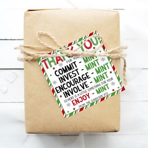 May include: A green and red striped gift tag with white snowflakes and red dots. The tag says "Thank You for You. Commit - Mint, Invest - Mint, Encourage - Mint, Involve - Mint. So here is a little something for your Enjoy - Mint. From the Sunnyside PTO."