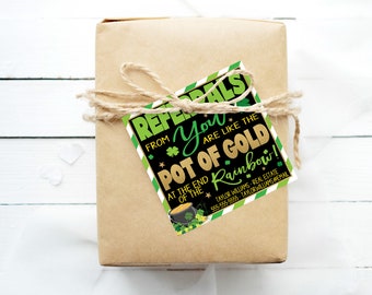 Op de afbeelding: Een bruine cadeaudoos met een groen-gouden cadeaulabel met de tekst "Referrals from you are like the pot of gold at the end of the rainbow!" met een klavertjevier en een pot goud.  Taylor Williams Real Estate staat vermeld met een telefoonnummer.