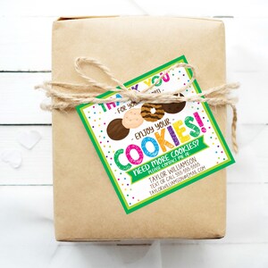 May include: A wrapped gift in brown paper tied with twine, featuring a colorful tag. The tag reads "Thank you - Enjoy your cookies!" with cookie illustrations and contact information for Taylor Williamson.