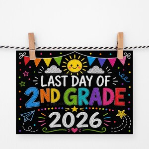 Può includere: Un cartello nero in stile lavagna con la scritta "LAST DAY OF 2ND GRADE 2026" in lettere colorate e giocose. Il cartello è decorato con un sole sorridente, nuvole, stelle e un aeroplanino di carta. È appeso a una corda con mollette.