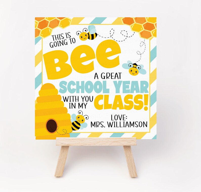 Peut inclure: Une pancarte jaune et bleue avec une ruche et des abeilles. La pancarte dit "This is going to bee a great school year with you in my class! Love: Mrs. Williamson"