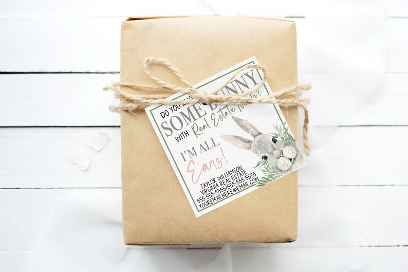 May include: A brown paper gift box tied with twine and a gift tag that says "Do you know some bunny with Real Estate needs? I'm all ears!" with a cartoon bunny illustration. The tag also includes contact information for a real estate agent.