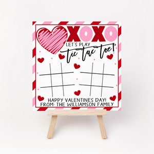 May include: A white card with red and pink stripes and hearts. The card says "XOXO Let's Play Tic Tac Toe! Happy Valentines Day! From: The Williamson Family".
