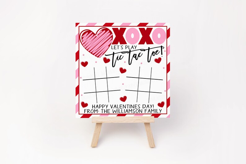 May include: A white card with red and pink stripes and hearts. The card says "XOXO Let's Play Tic Tac Toe! Happy Valentines Day! From: The Williamson Family".