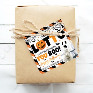 May include: A wrapped gift in brown paper tied with twine, featuring a Halloween-themed gift tag. The tag has a pumpkin, ghost, and the words "LOTTO FOR EVERYTHING YOU BOO! Happy Halloween!" in black and orange.
