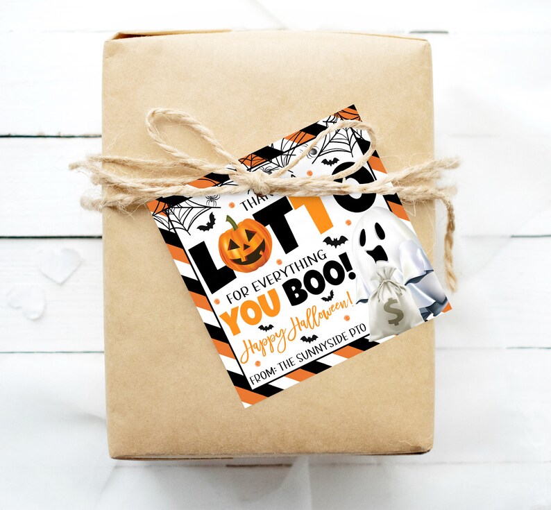 May include: A wrapped gift in brown paper tied with twine, featuring a Halloween-themed gift tag. The tag has a pumpkin, ghost, and the words "LOTTO FOR EVERYTHING YOU BOO! Happy Halloween!" in black and orange.