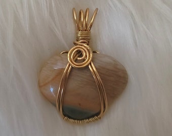May include: A gold wire wrapped pendant featuring a heart-shaped stone with brown, beige, and green swirls.