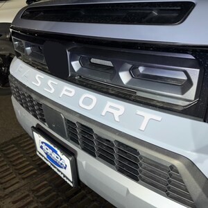 May include: A gray SUV with a black grille and the word "SPORT" in white letters on the front bumper.
