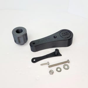 May include: A collection of black and gray 3D-printed parts, including a cylindrical piece, a lever with the text "YAN HOBBY", and various fasteners. The parts are arranged on a white surface.