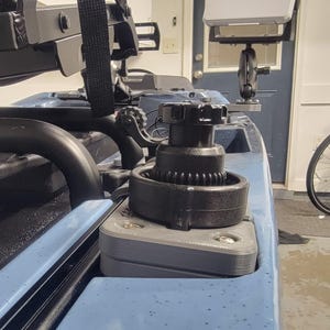 May include: A close-up of a blue kayak with black hardware. A black winch is mounted on a gray base. A Lowrance fish finder is mounted on the kayak. The kayak has a black strap and other black accessories.
