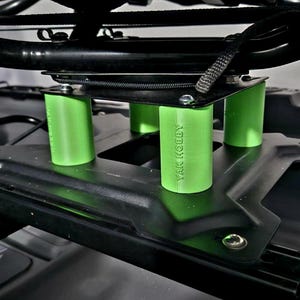 May include: Close-up of a black kayak seat base with four green support posts. The posts are labeled "YAK HOBBY".