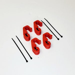 May include: Four red plastic cable clips and four black zip ties. The clips are designed to hold cables in place.