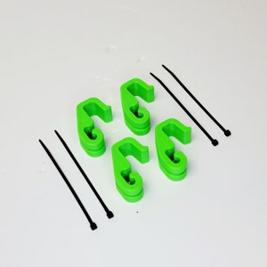 May include: Four bright green plastic cable clips and two black cable ties. The clips are shaped like a hook and are designed to hold cables in place.