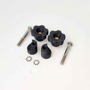 Puede incluir: Dos pomos de plástico negro con un tornillo plateado y una arandela plateada. Los pomos tienen la palabra "MORRE" impresa.