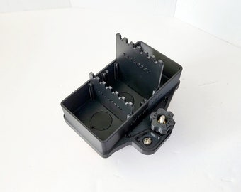 May include: Black plastic box with two compartments and a knob on the side. The compartments have slots for holding small items. The box is labeled "TAK Hobby".
