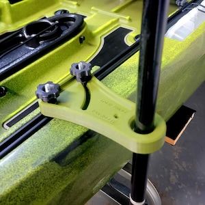 Könnte beinhalten: Ein grünes Kajakzubehör mit zwei schwarzen Knöpfen und einer schwarzen Stange. Das Zubehör ist mit "10 INCH THROW" und "KAYAK-P111E" beschriftet.