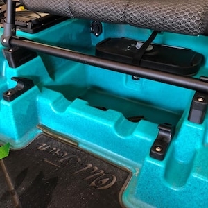 Può includere: Un kayak turchese con un sedile nero e un vano portaoggetti nero. Il kayak ha una barra nera in cima e un cinturino verde sul lato.