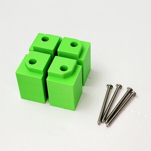 May include: Four bright green plastic blocks with rounded edges and a small hole in the center of each block. Four silver screws are included.