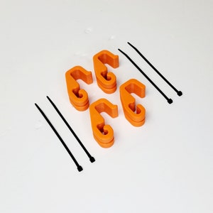 May include: Four orange plastic cable clips and two black zip ties. The clips have a hook shape and are designed to hold cables in place.