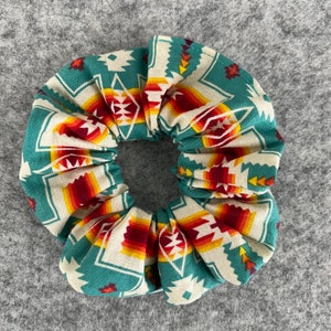 May include: A teal, white, red, and yellow patterned scrunchie with a geometric design.