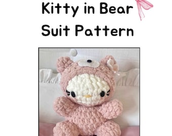 Könnte beinhalten: Ein rosa gehäkeltes Hello Kitty Plüschtier, das ein rosa Bärenkostüm trägt. Das Spielzeug sitzt auf einer weißen und rosa Decke.
