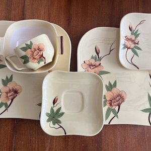 May include: A set of five vintage ceramic plates with a floral design. The plates are in shades of cream, brown, and green. The design features stylized flowers and leaves.