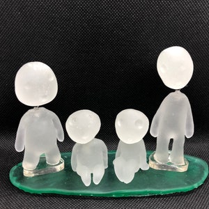 May include: Four white frosted glass figurines standing on a green base. The figurines are all different sizes and shapes, and they have a whimsical, almost cartoonish look.