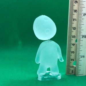 May include: A clear glass figurine of a person with a round head and a simple body shape. The figurine is about 6 inches tall and is standing on a clear plastic base.