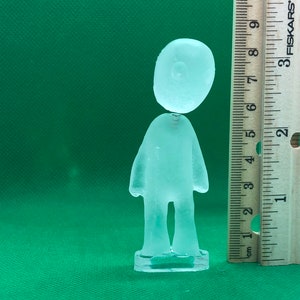 May include: A clear glass figurine of a person standing on a base. The figurine is about 6 inches tall.