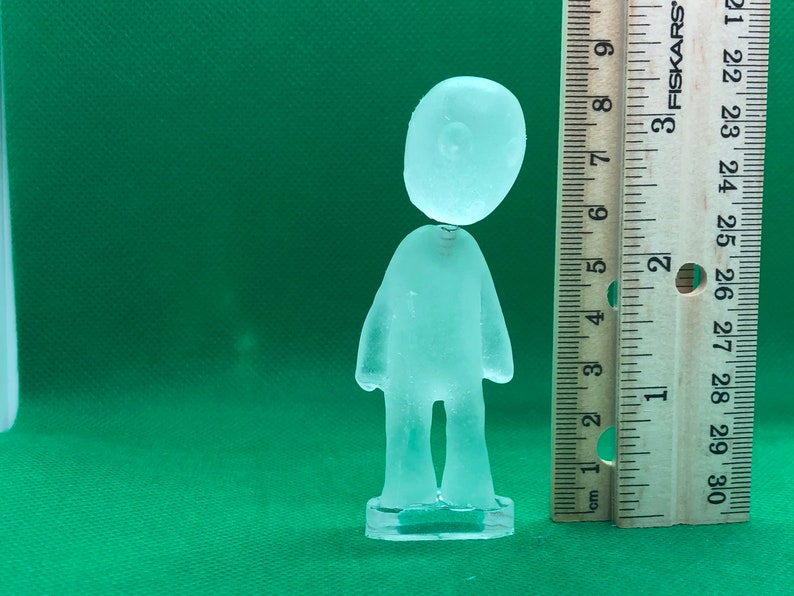 May include: A clear glass figurine of a person standing on a base. The figurine is about 6 inches tall.