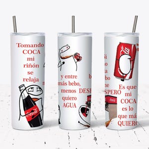 Może przedstawiać: Trzy białe kubki izolowane ze słomkami ze stali nierdzewnej. Każdy kubek zawiera ilustrację z kreskówki i tekst w języku hiszpańskim związany z Coca-Colą. Projekty obejmują butelkę i puszkę Coca-Coli.