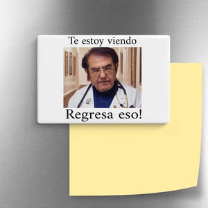 May include: A white rectangular magnet with the image of a man wearing glasses and a doctor's coat. The magnet has the text "Te estoy viendo" and "Regresa eso!" in black font.