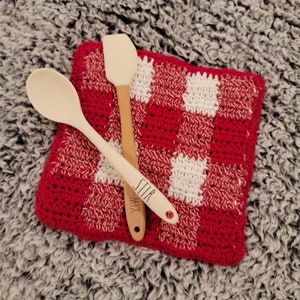 May include: Red and white checkered crochet pot holder with two wooden spoons, one with the word "STIR" and the other with the word "MIX" written on them.