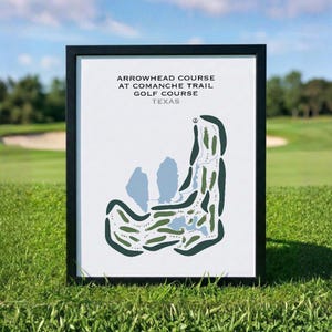 May include: Framed print of the Arrowhead Course at Comanche Trail Golf Course in Texas. The course map is in green and blue on a white background, set in a black frame. The print is displayed on a grassy surface.