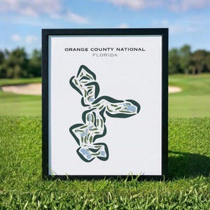 May include: A framed print featuring a stylized golf course map of Orange County National, Florida. The white background displays a dark green and light blue course layout with the text ORANGE COUNTY NATIONAL FLORIDA printed in black and gray.
