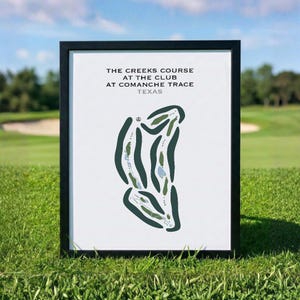 May include: A framed print featuring a golf course map titled THE CREEKS COURSE AT THE CLUB AT COMANCHE TRACE TEXAS. The graphic shows dark green fairways, light green greens, and light blue water hazards on a white background in a black frame.