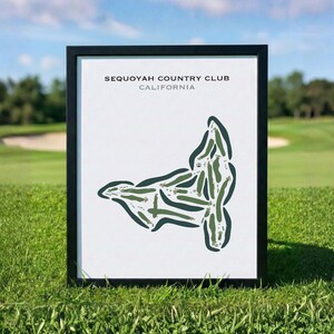May include: Framed print of the Sequoyah Country Club golf course in California. The course layout is depicted in green on a white background, with the club name and state at the top. The frame is black, and the print is displayed on a grassy surface.