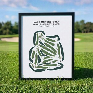 May include: A framed print of the Lake Merced Golf and Country Club in California. The print features a green and brown golf course layout on a white background, with the club's name and location printed at the top. The frame is black.