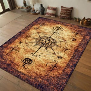 May include: A rectangular rug featuring a compass rose design in black on a tan backdrop. The rug has a dark brown border and various symbols. It is placed on a wooden floor. The rug's dimensions are in centimetres.