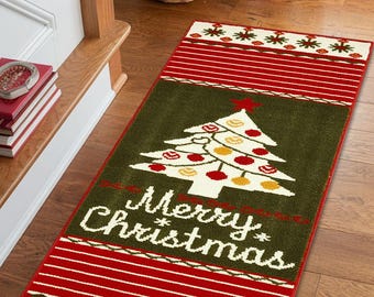 May include: A rectangular Christmas-themed rug with a green center featuring a white Christmas tree decorated with red and yellow ornaments. The rug has red and white striped borders and the words "Merry Christmas" in white.