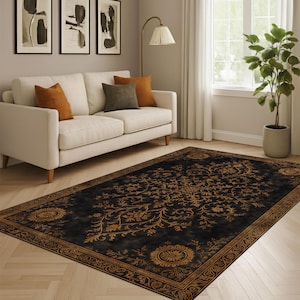 May include: A rectangular black rug featuring an elaborate gold floral design. The rug has a detailed border and is placed in a living room setting with a white sofa and decorative cushions.