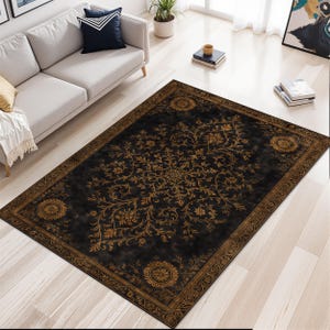 May include: A black rectangular rug with a gold floral design. The rug has a central medallion and a decorative border. It's placed on a light wood floor, with a sofa and decor visible in the background. The rug's design is reminiscent of a classic Persian style.