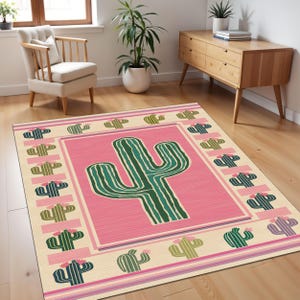May include: A pink and cream area rug with a large green cactus in the center. The rug has a border of smaller green cacti with pink flowers.