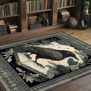 May include: A black and white rug with a detailed illustration of a raven perched on an open book. The raven is surrounded by intricate floral designs and leaves. The rug has a dark blue border with a repeating pattern.