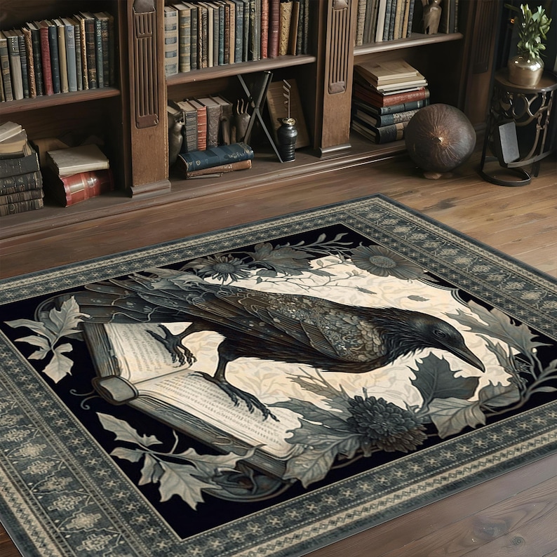 May include: A black and white rug with a detailed illustration of a raven perched on an open book. The raven is surrounded by intricate floral designs and leaves. The rug has a dark blue border with a repeating pattern.