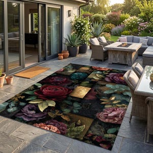Pode incluir: Um tapete retangular com um padrão floral escuro e atmosférico, apresentando grandes rosas detalhadas em tons de vermelho profundo, roxo e rosa, intercaladas com blocos geométricos dourados e folhagem verde sobre um fundo preto.