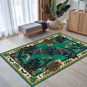 May include: A green and cream area rug with a black bat design. The bat is surrounded by leaves and flowers. The rug has a yellow and red border.