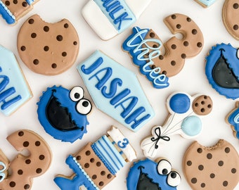 May include: A set of 15 decorated sugar cookies featuring a blue cookie monster character, milk bottles, a cookie cake, balloons, and the name "Jasiiah" and the word "three".